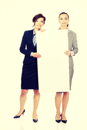 Two businesswomen showing white empty banner.の写真素材