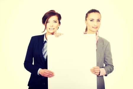 Two businesswomen showing white empty banner.の写真素材