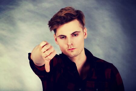 Young upset man showing thumbs down.の写真素材