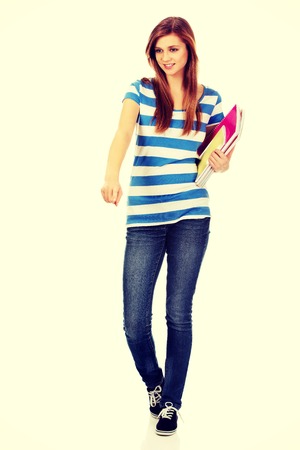 Teenage happy woman holding textbooks and pointing for something.の写真素材