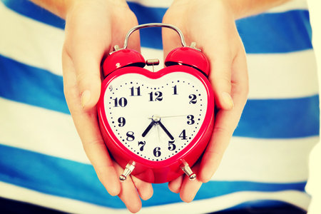 Teenage woman showing alarm clock.