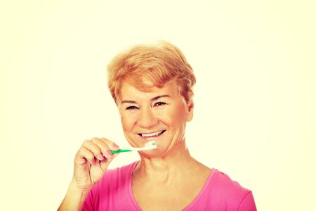 Smiling senior woman brushing teeth.の写真素材