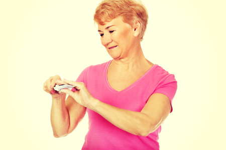 Smiling senior woman holding toothpaste and toothbrush.の写真素材