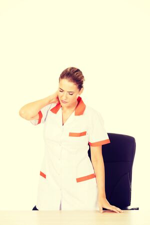 Tired young female doctoror nurse standing behind the desk.の写真素材