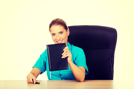 Young female doctor or nurse shows notebook.の写真素材