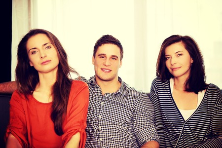 Sisters and brother sitting on the sofa.の写真素材