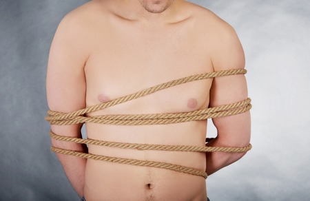Tortured shirtless man tied with a rope.の写真素材