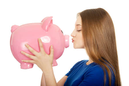 Happy teenage woman kissing piggybank.の写真素材