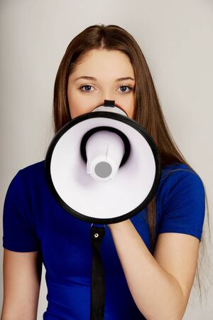 Screaming young teenage woman with megaphone.の写真素材