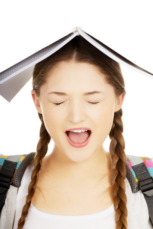 Frustrated teen girl with book over her head.の写真素材