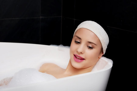 Beautiful bathing woman relaxing in bathtub.
