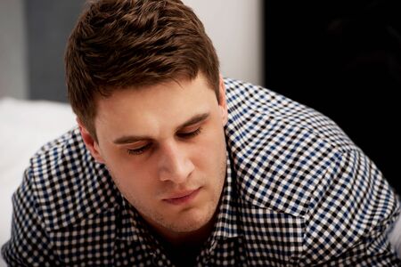 Handsome young smiling man sitting in bedroom.の写真素材