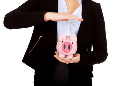 Young business woman protects piggybank.の写真素材