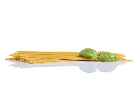 Uncooked dry fettuccine pasta  with green basil.の写真素材