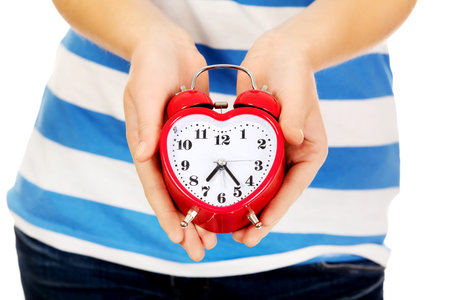 Teenage woman showing alarm clock.