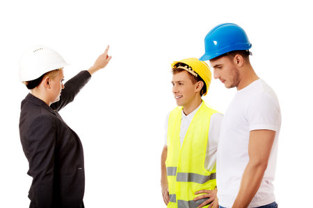 Female engineer talking with two builders and pointing for something.