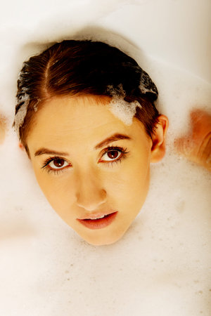 Young woman washing hair in bath.