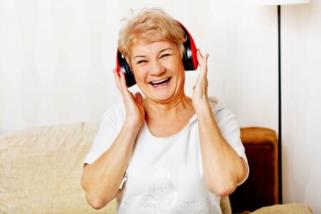 Happy senior woman wearing red headphones.の写真素材