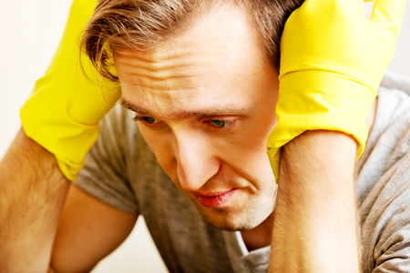 Tired man sitting behind the desk with cloth and gloves.の写真素材