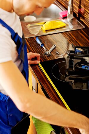 Young repair man measuring kitchen cabinet.の写真素材