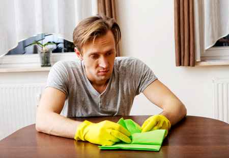 Tired man sitting behind the desk with cloth and gloves.の写真素材