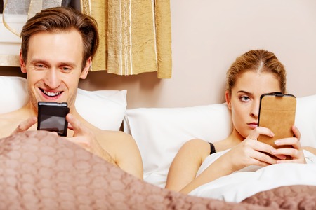 Young couple in a bed with mobile phones.の写真素材