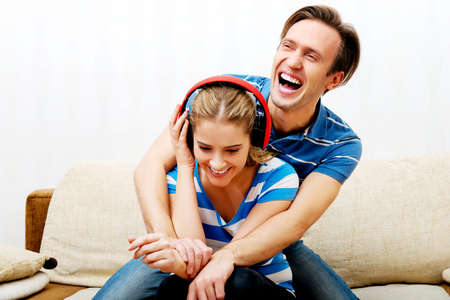 Woman listen music, her happy husband hugging her.の写真素材