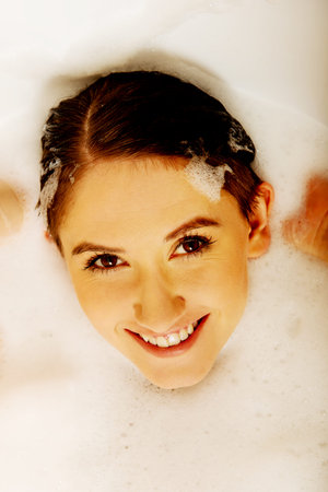 Young woman washing hair in bath.