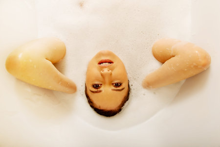 Young woman washing hair in bath.の写真素材