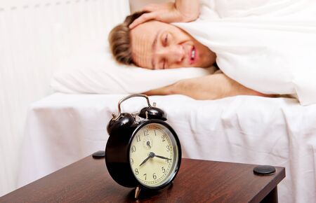 Man trying to sleep, when alarm clock ringing.の写真素材