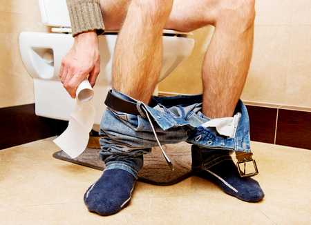 Man sitting on a toilet seat.の写真素材