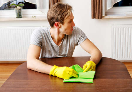 Tired man sitting behind the desk with cloth and gloves.の写真素材