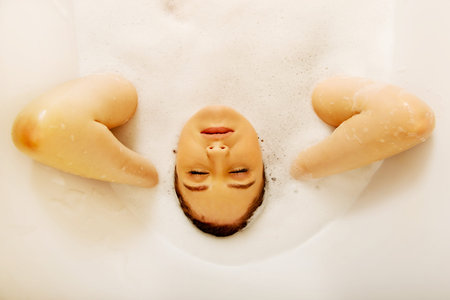 Young woman washing hair in bath.