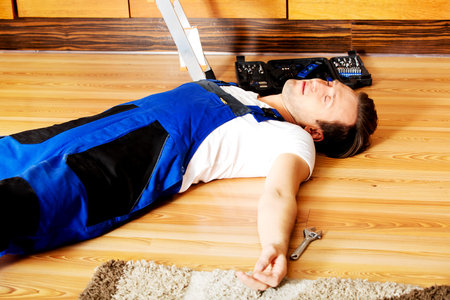 Young handyman fell from a ladder and lies on the floor.の写真素材