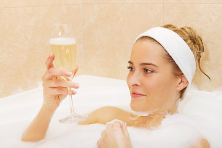 Woman relaxing in bath with glass of champagne.の写真素材