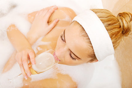 Woman relaxing in bath with glass of champagne.
