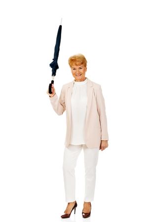 Happy elderly business woman pointing up with umbrella.の写真素材