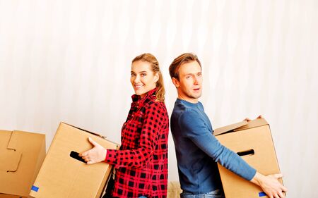 Happy couple carrying cardboard boxes in new home.の写真素材