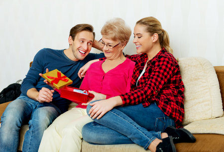 Happy family - couple with old woman who holding gift box and baby shoe.