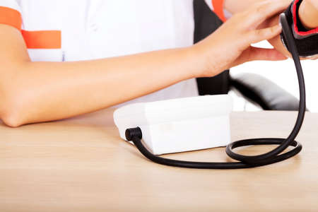 Female doctor or nurse sitting behind the desk holding blood pressure gauge.の写真素材