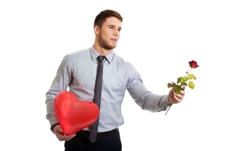 Young happy man with red rose and heart balloon.の写真素材