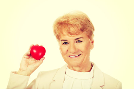 Smile elderly woman holding heart model.の写真素材