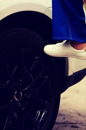 Woman is changing tire of car with wheel wrench.の写真素材
