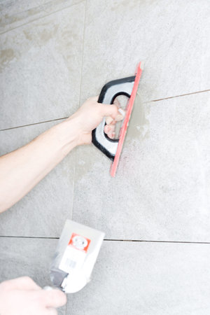 Tiler installs ceramic tiles at home.の写真素材