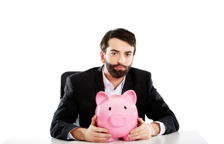 Young businessman with piggybank by a desk.の写真素材