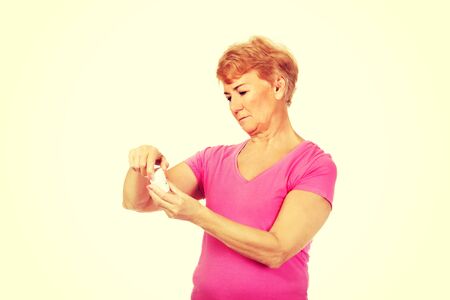 Smiling senior woman holding jar of pills.の写真素材