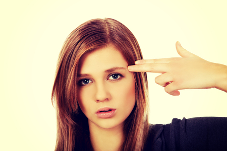 Teenage woman committing suicide with finger gun gesture.の写真素材