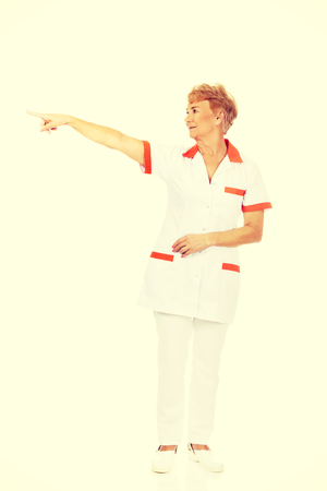 Smile elderly female doctor or nurse pointing for copyspace or something.の写真素材