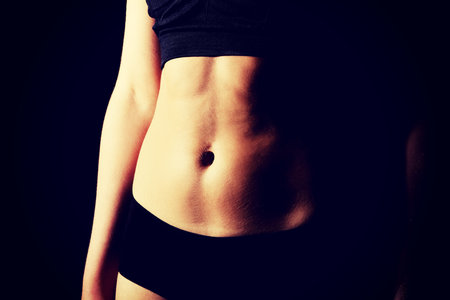 Belly of slim young woman in black sports underwear.