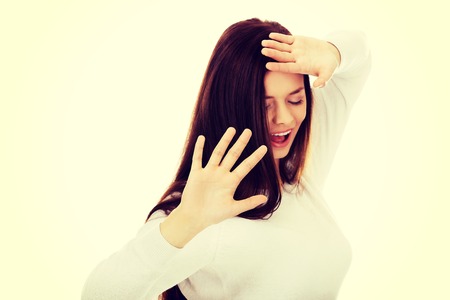 Amused young woman hides behind her hands.の写真素材